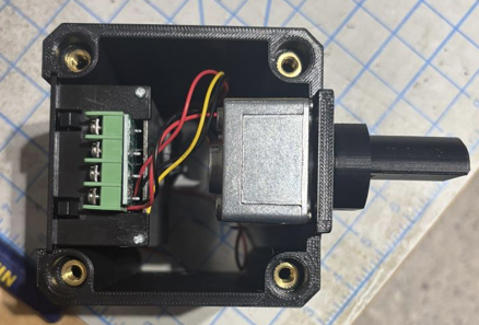 Inside the fixture enclosure: motor, terminal block wiring, and heat-set inserts