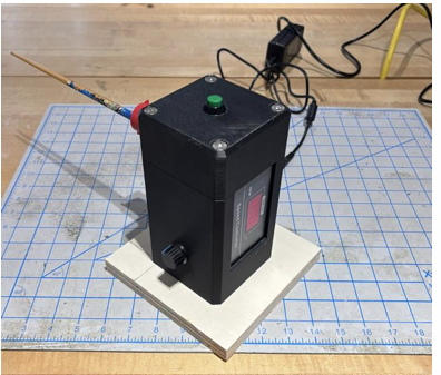 The finished bonding fixture: a compact black 3D-printed enclosure with speed display, control knob, and start button on a cutting mat
