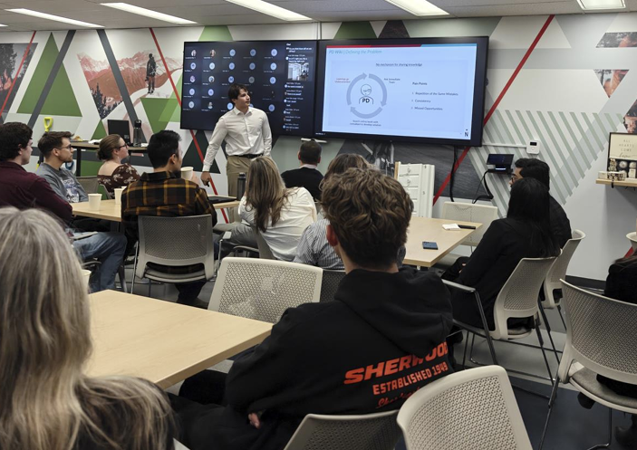 Ben presenting the PD Wiki and AI agent to a full room at the company town hall, with remote attendees on screen